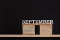 Word September made of wooden letters on black background. Front view. Autumn calendar. Copy space