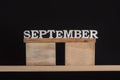 Word September made of wooden letters on black background. Front view. Autumn calendar. Fall month