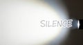 The word silence illuminated by a bright flashlight. Space for text. Royalty Free Stock Photo