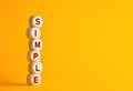 The word simple on wooden cubes against yellow background. Simplicity principle in life, business or education Royalty Free Stock Photo