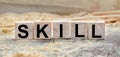 The word SKILL is written on wooden cubes. Wooden cubes lie on the table with sawdust and wooden blocks. Designed to promote your