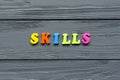Word `skills` of colored plastic magnetic letters on grey wooden background