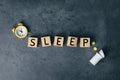 Word Sleep made of wooden cubes near pills and alarm clock on grey background, flat lay. Insomnia concept Royalty Free Stock Photo