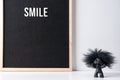 The word smile on black letter board with happy troll on white desk