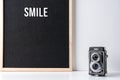 The word smile on camera and on black letter board. Text, quote and creative concept.