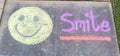 The word Smile" and smiley face emoji sidewalk chalk
