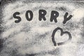 word Sorry is written on a baking tray sprinkled with icing sugar or flour