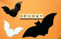 Word Spooky. Wooden blocks with an inscription on an orange background are decorated with bat mice made of paper. The bulletin