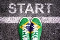 Word Start written on an asphalt road with legs and shoes colored with brazilian flag