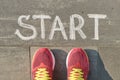 Word start written on gray pavement with woman legs in sneakers, view from above