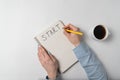 Word START written in notebook. Female hand making a note in Notepad, Cup of coffee on white background