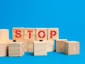 Word stop on wooden cubes against blue background. Royalty Free Stock Photo