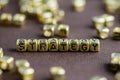 Word STRATEGY made from small golden letters on the brown background, selective focus. Business concept background Royalty Free Stock Photo