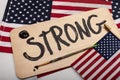The word strong painted in black paint on wooden sign American flags in the background