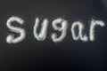 The word sugar written in white refined grans of sugar Royalty Free Stock Photo