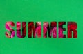 The word Summer cut out of a green piece of paper with roses visible through the holes