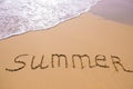 Word Summer hand written in the sand with a sea wave. Close up sand texture on beach in summer Royalty Free Stock Photo