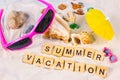 Word Summer Vacation on yellow sandy textured background with bright seashells and stones. Sea holiday tourism and tropics Royalty Free Stock Photo