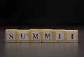 The word SUMMIT written on wooden cubes isolated on a black background