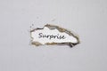 The word surprise appearing behind torn paper