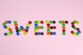 The word sweets are contained by colored candies on a pink background Royalty Free Stock Photo