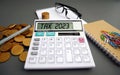 Word Tax 2023 on the calculator. Business and tax concept .Calculator, currency, book, tax form, and pen on gray desk table. Royalty Free Stock Photo