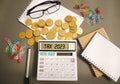 Word Tax 2023 on the calculator. Business and tax concept .Calculator, currency, book, tax form, and pen on gray desk table. Royalty Free Stock Photo