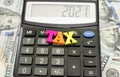 The word `tax` on the calculator. 2021 on the scoreboard. Close-up. Financial concept.