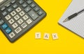 Word tax made with wood letters on yellow background and modern calculator with pen and notebook. Copy space. Economy, money Royalty Free Stock Photo