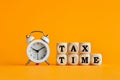 The word tax time written on wooden cubes with an alarm clock. Tax payment reminder or annual taxation concept Royalty Free Stock Photo