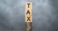 Word TAX written on wooden cubes on stacked coins on dark background. pay taxes concept - wooden blocks on coin stacks Royalty Free Stock Photo