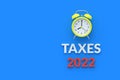 Word taxes 2022 near alarm clock on blue background. The concept of paying the tax Royalty Free Stock Photo