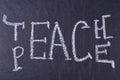 Word teach peace written on black chalkboard close up.