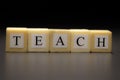 The word TEACH written on wooden cubes isolated on a black background
