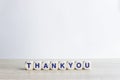 A word `Thank you` on a wooden table over the light background