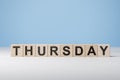 Word Thursday on wooden cubes. Weekday concept. Thursday inscription on wooden cubes on blue background. copy space