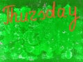 Word Thursday written by hand with brush in orange on a textured green background, copy space