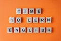Word time to learn English. Motivation. The phrase is laid out in wooden letters top view. Motivation. Orange flat lay Royalty Free Stock Photo