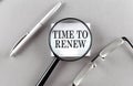Word TIME TO RENEW on sticky through magnifier on grey background Royalty Free Stock Photo