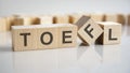 word TOEFL on wooden cubes, gray background.
