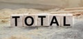 The word TOTAL is written on wooden cubes. Wooden cubes lie on the table with sawdust and wooden blocks. Designed to promote your