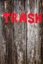 The word `trash` painted in red on a rustic wooden background