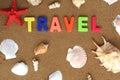 The word travel surrounded by seashells is written on the sand in bright multicolored letters. Royalty Free Stock Photo