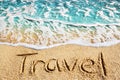 Word TRAVEL written on yellow sand, blue sea water wave, white foam top view close up, handwriting letters text, summer vacation