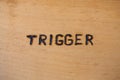 The word trigger handwritten on flat bare plywood surface with woodburner Royalty Free Stock Photo