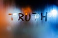 The word truth written on night wet window glass close-up with bokeh background