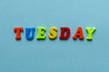 Word `tuesday` of colored plastic magnetic letters on blue paper background