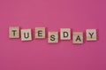 The word Tuesday. Text day of the week in wooden letters.Black letters on wood, blue background with shadows. blank for design