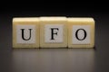 The word UFO written on wooden cubes isolated on a black background