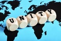 The word unity written on wooden cubes on world map background. International teamwork, alliance or collaboration around the globe Royalty Free Stock Photo